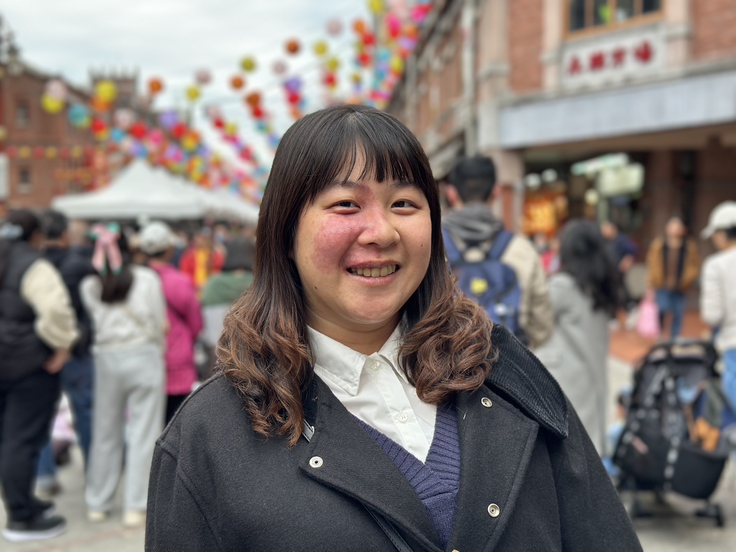 Portrait Photo of Hsiao-Chian with a blurred background of a busy street with people and colourful decoration.